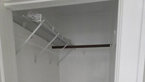 A walk-in closet with a metal shelving unit and a wooden shelf.