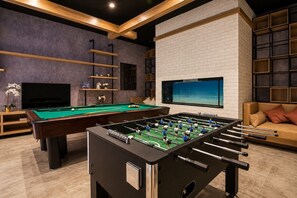 A room with a pool table, foosball table, television, and a sofa. - HAVN - Studio in Q Gardens Boutique, Arjan (Dubai)