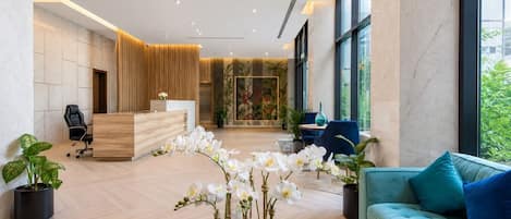 A modern reception area with a wooden desk, a blue sofa, and potted plants.