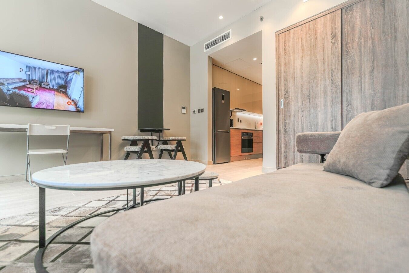Una sala de estar moderna con un televisor de pantalla plana, una mesa redonda y un sofá.