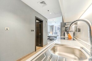 A modern kitchen with a built-in sink, a coffee machine, and a view into the adjacent dining area. - HAVN - Studio in Q Gardens Boutique, Arjan (Dubai)