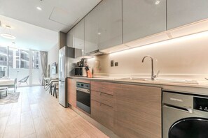 A modern kitchen with a built-in dishwasher, a microwave, and a coffee maker on the countertop. - HAVN - Studio in Q Gardens Boutique, Arjan (Dubai)