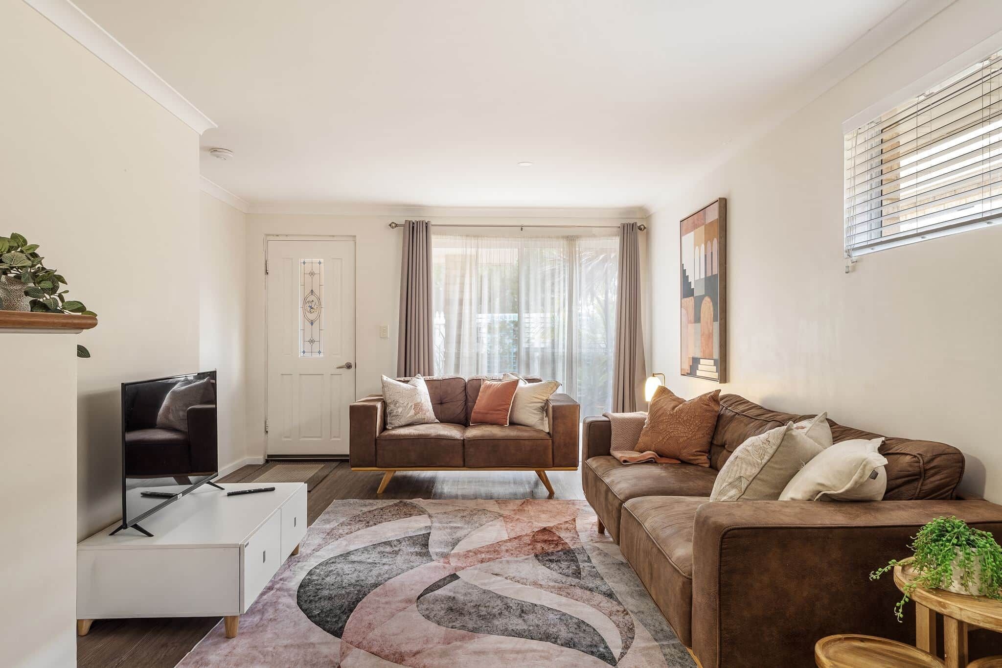 A modern living room with a sofa, a coffee table, and a TV stand.