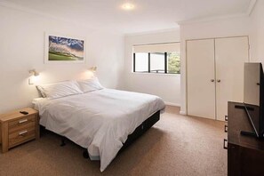 A bedroom with a bed, bedside tables, a wardrobe, a window, and a painting on the wall. - Gas Bay Beach House Margaret River (Gnarabup)