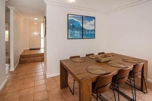 A dining area with a wooden table, woven placemats, and chairs. - Gas Bay Beach House Margaret River (Gnarabup)