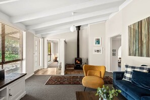 A living room with a sofa, armchair, and a fireplace. There is a staircase leading to another room. - Forest View Retreat Margaret River (Margaret River)
