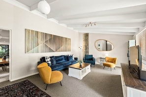 Ein modernes Wohnzimmer mit Sofa, Sesseln, Couchtisch und Kunstwerken an der Wand.