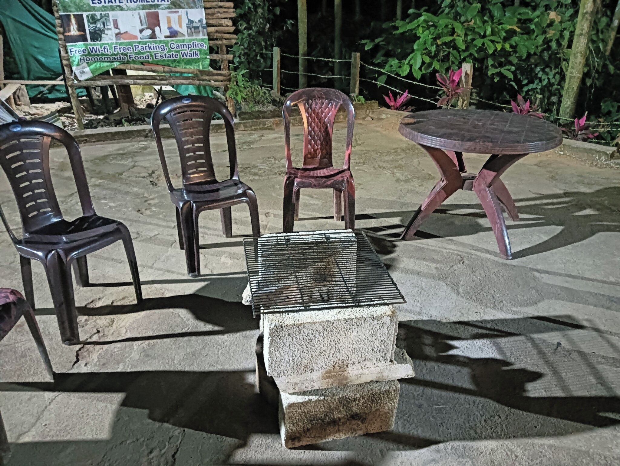 Buiten zitplaatsen met stoelen en een tafel, een betonnen blok en een bord in de achtergrond.