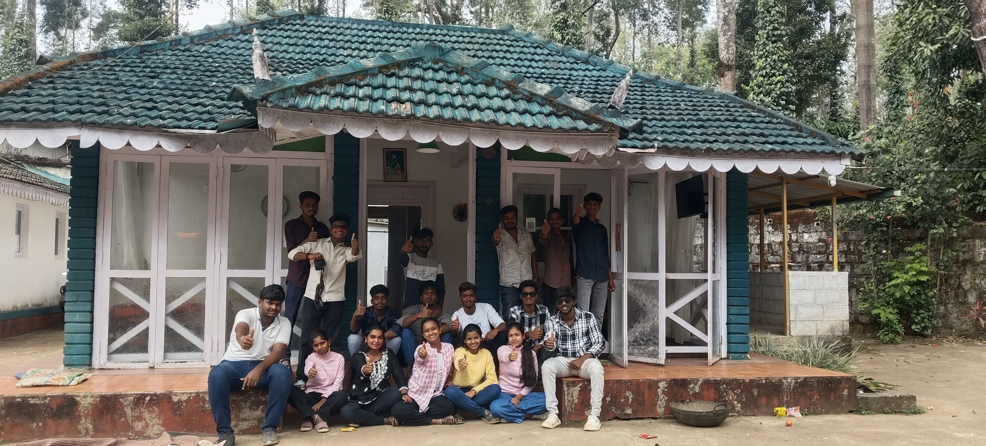 A group of people gathered around a small, traditional-style building with a tiled roof and a covered porch.
