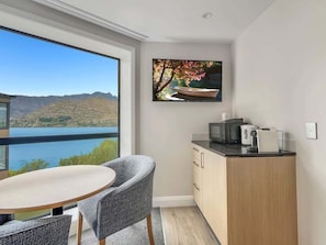 Ein modernes Zimmer mit Essbereich, einer Küche und einem großen Fenster mit Blick auf einen See und Berge.