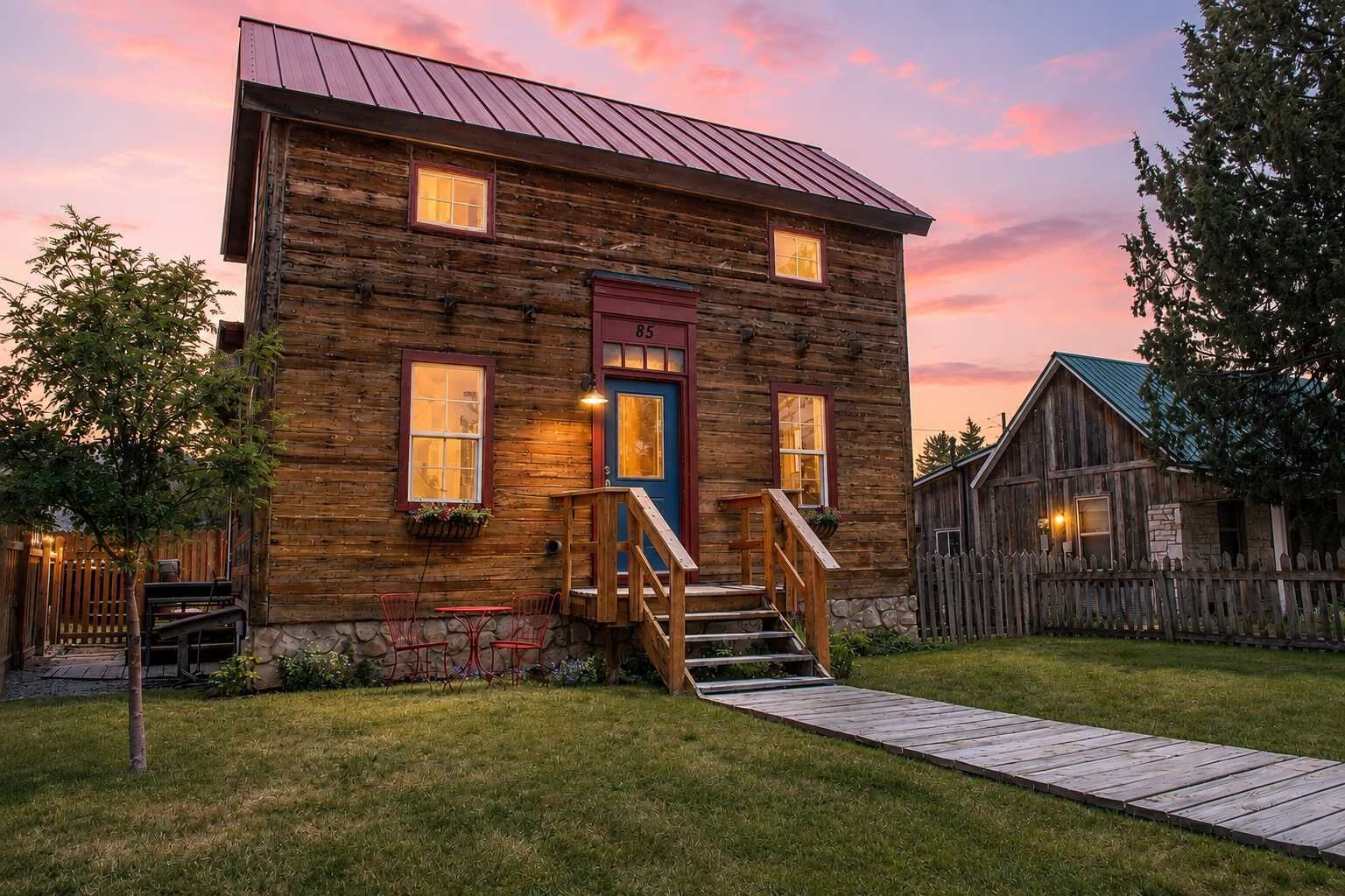 A rustic log cabin with a wooden staircase leading to a front door, a small porch, and a wooden deck.