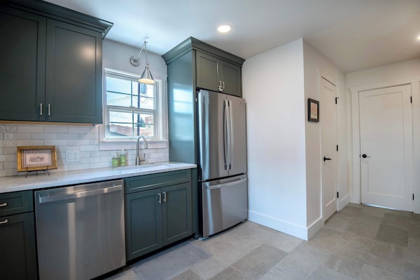 A modern kitchen with stainless steel appliances, a window, and a door.