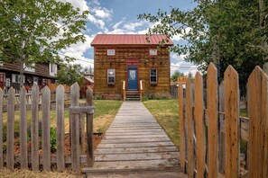 Una casa di legno con tetto rosso, una recinzione in legno e un vialetto in legno che conduce all'ingresso.