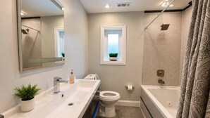 Un baño moderno con un lavamanos amplio, inodoro y bañera.