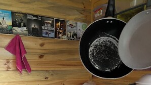 Une cuisine équipée d’une cuisinière, d’une bouilloire et d’un mur en bois orné d’affiches.