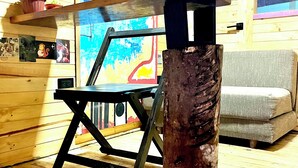 Un intérieur en bois, avec une table en bois unique et un tableau abstrait aux couleurs vives accroché au mur.
