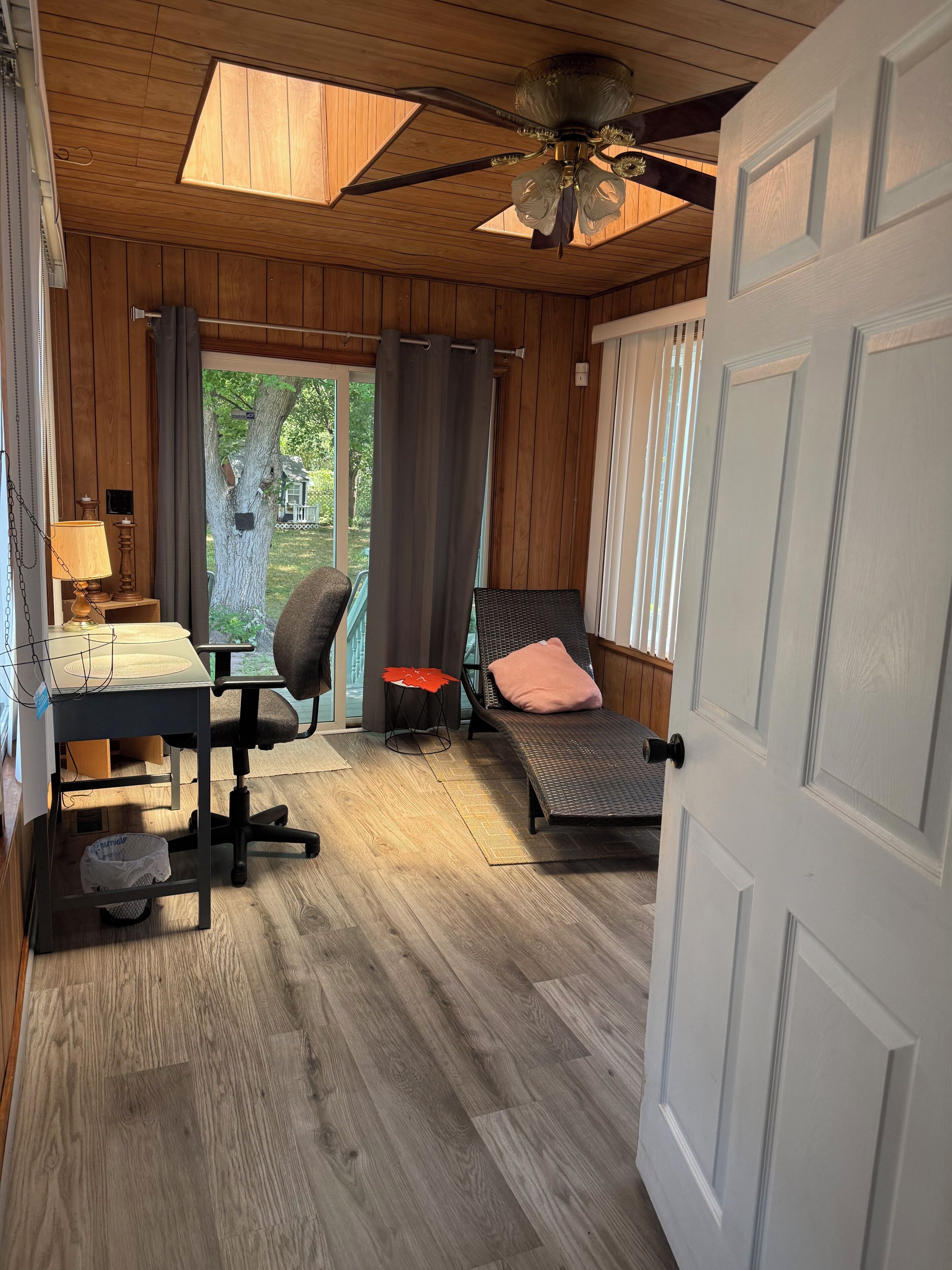 A room with a desk, office chair, and a bed with a pillow.