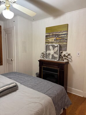 Une chambre avec un lit, un radiateur, une cheminée et un tableau au mur.