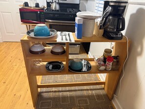 Un plan de travail de cuisine équipé d’un four à micro-ondes, d’une bouilloire, d’une machine à café et de divers ustensiles de cuisine.