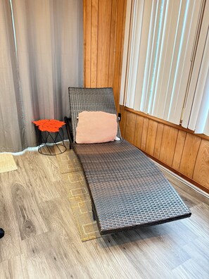 Ein Zimmer mit einem Einzelbett, einem kleinen Tisch und einem Fenster mit Jalousien.