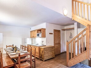A compact kitchen with wooden cabinets, a central island, and a dining area with a wooden table and chairs. - Les Fermes de Saint Sorlin by Interhome (Saint Sorlin d'Arves)