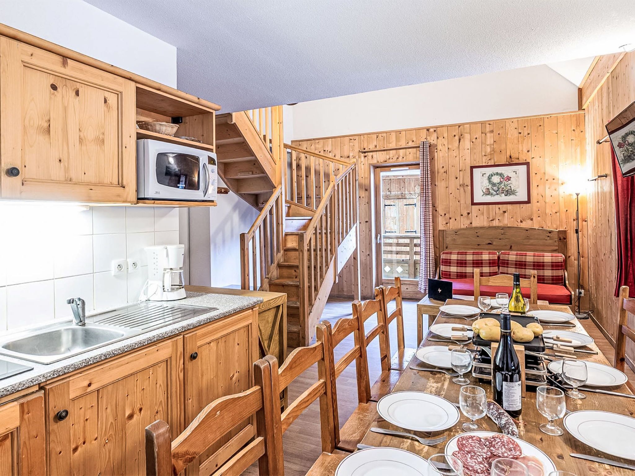 A wooden interior with a kitchen, dining area, and a staircase.
