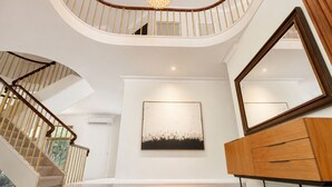 Una majestuosa escalera de madera con barandilla y un candelabro.