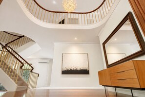 Una majestuosa escalera de madera con barandilla y un candelabro.