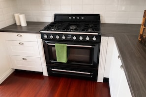 Una cocina con estufa negra, gabinetes blancos y encimera de madera.