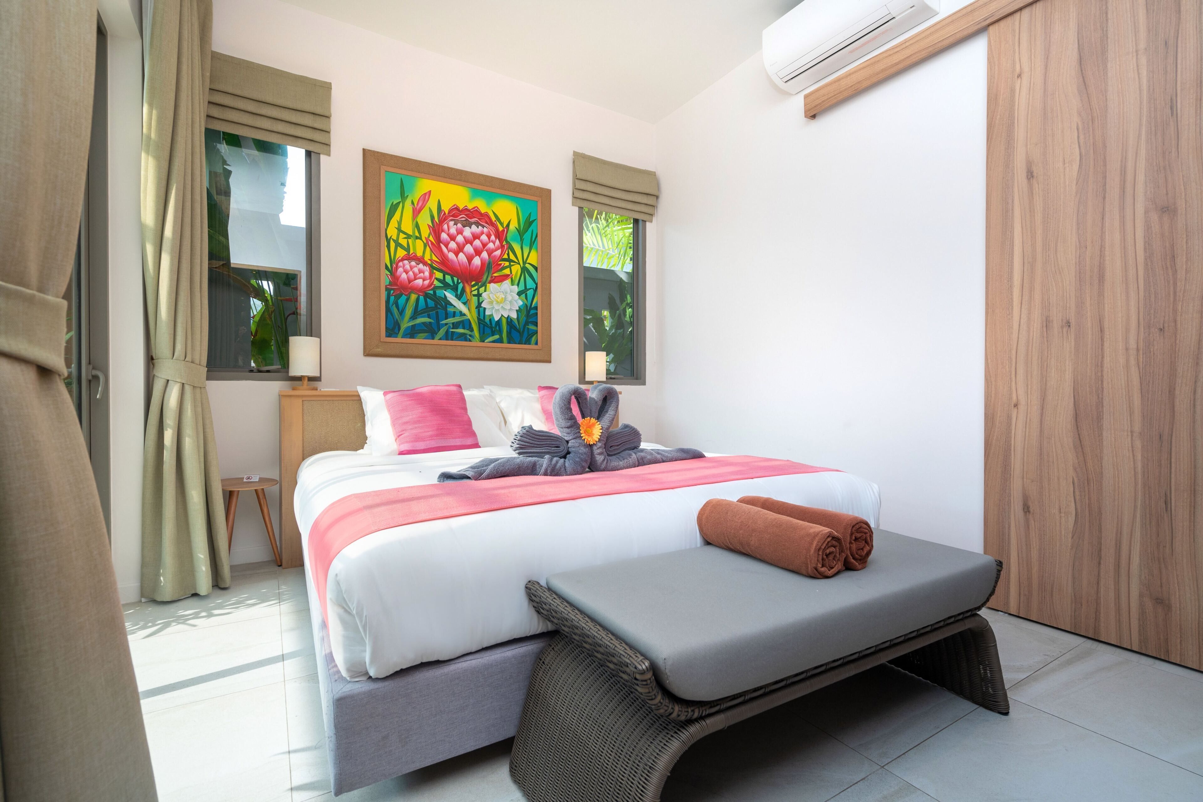 Un dormitorio moderno con una cama, un banco, un cuadro y un equipo de aire acondicionado.