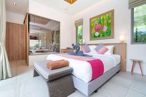 Een moderne slaapkamer met een groot bed, een badkamer met een glazen douchecabine en een eethoek.