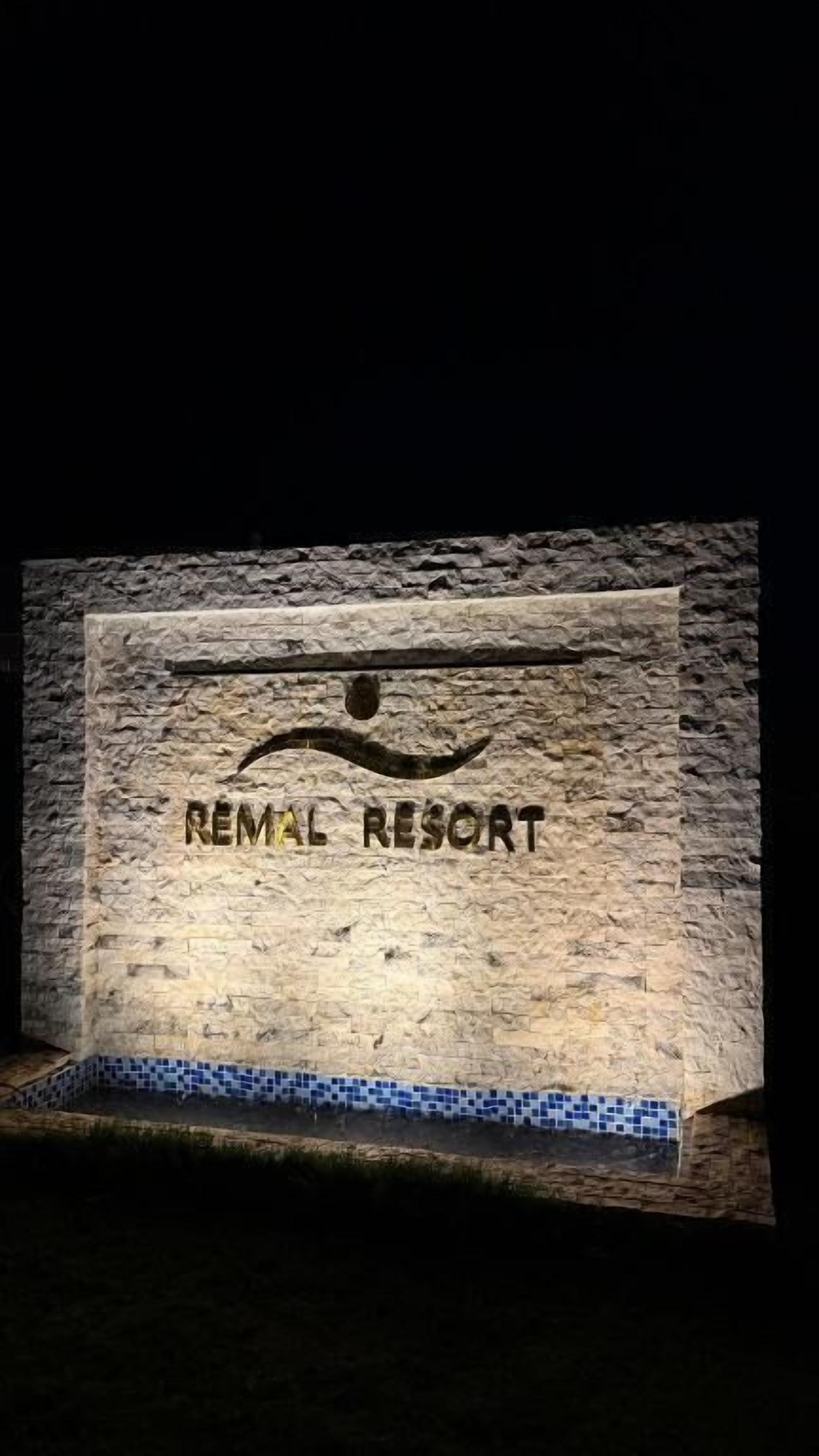 A stone wall with the inscription 'REMMAL RESORT' and a decorative element above it.