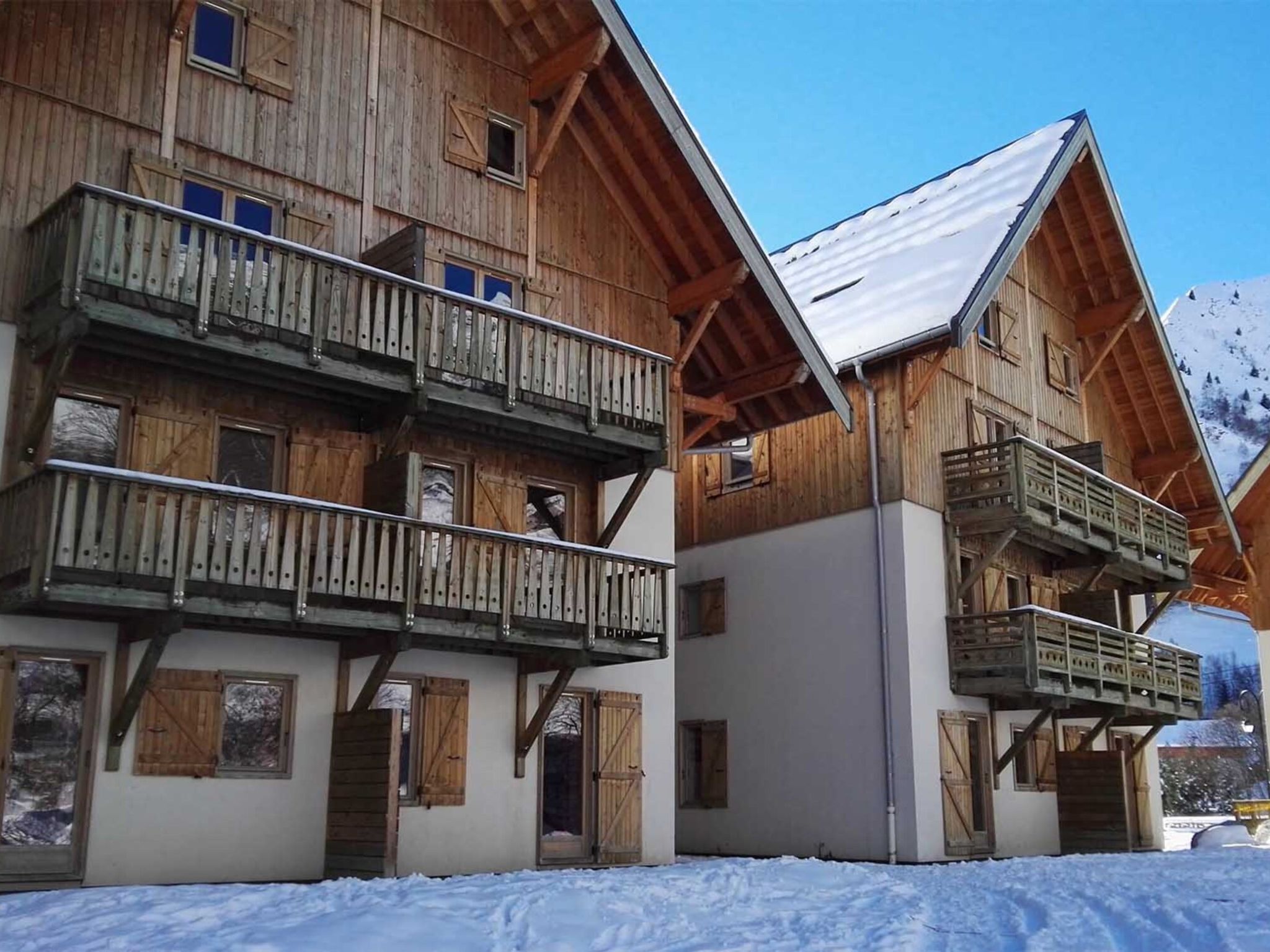 A wooden chalet with a balcony and a snow-covered roof.