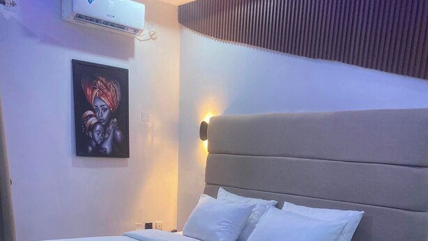 A bed with a headboard, white bedding, and a wall-mounted light.
