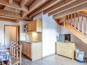 Eine kleine Küche mit Holzausstattung, einer Mikrowelle und einem Essbereich mit Stühlen.