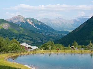 Un paysage de montagne avec un lac, une clôture en bois et un petit bâtiment.