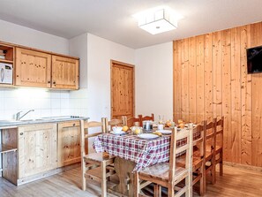 Eine Küche mit Holzschränken, einem Esstisch für zwei Personen und einem Frühstückstisch mit verschiedenen Gegenständen.