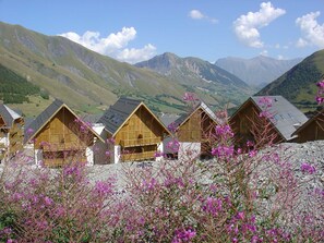 A row of wooden chalets with sloped roofs, set against a mountainous backdrop. - Les Fermes de Saint Sorlin by Interhome (Saint Sorlin d'Arves)