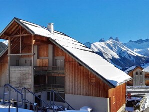 Eine Holzhütte mit Balkon vor einer schneebedeckten Berglandschaft.