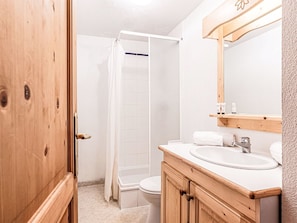 A bathroom with a wooden door, a white sink, a mirror, and a shower. - Les Fermes de Saint Sorlin by Interhome (Saint Sorlin d'Arves)