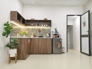Eine kleine Küche mit Holzausstattung, einer integrierten Mikrowelle und einem Kühlschrank.