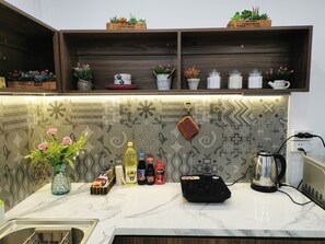 Een keuken met een marmeren aanrecht, een koffiezetapparaat en diverse keukengerei.