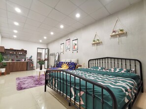 Ein modernes Schlafzimmer mit einem Metallbettgestell, einer Küchenzeile mit Schränken und einem Kühlschrank, sowie ein Badezimmer mit Spiegel und Handtuchhalter.