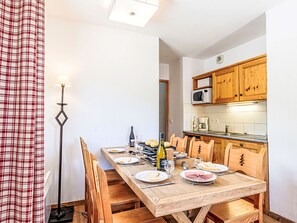 A dining area with a wooden table set for four, a wine bottle, and a bread basket. - Les Fermes de Saint Sorlin by Interhome (Saint Sorlin d'Arves)