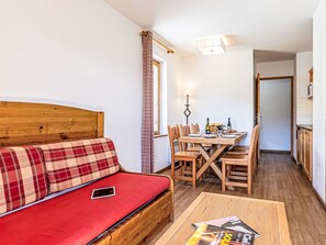 Une pièce chaleureuse avec un canapé rouge, une table à manger en bois et des chaises.