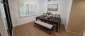 A dining area with a dark wooden table, four chairs, a bench, a vase with greenery, and a painting on the wall. - Renovated 1-bedroom condo in Anaheim, perfect for your stay-5 miles from Disney! (Anaheim)