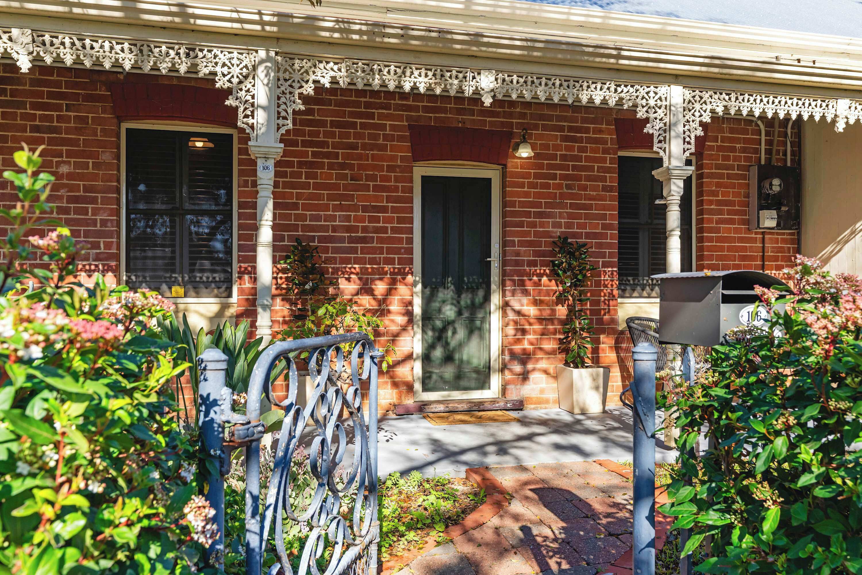 A brick house with a decorative porch, a front door, and a mailbox.