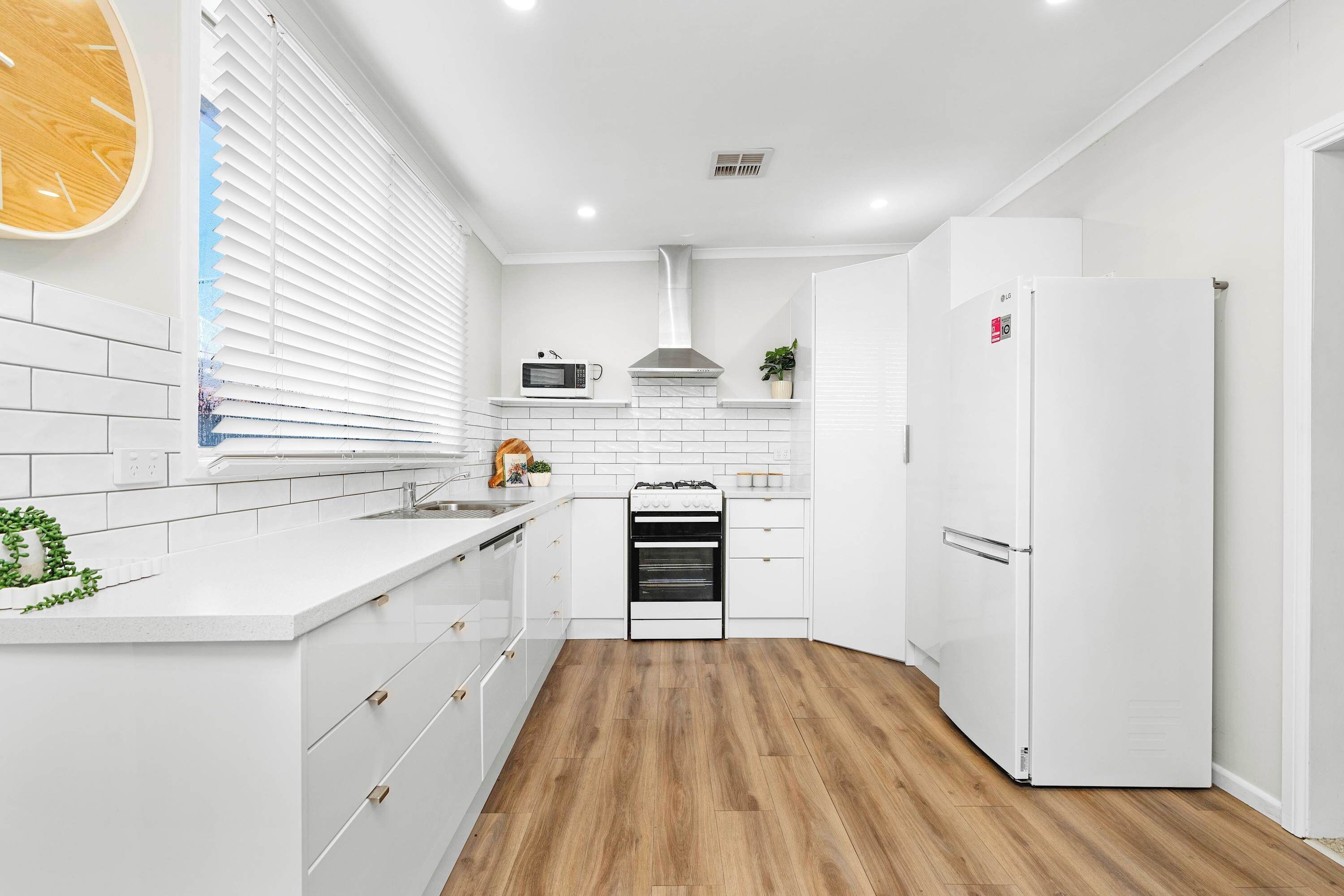A modern kitchen with white cabinetry, a built-in oven, a microwave, and a refrigerator.