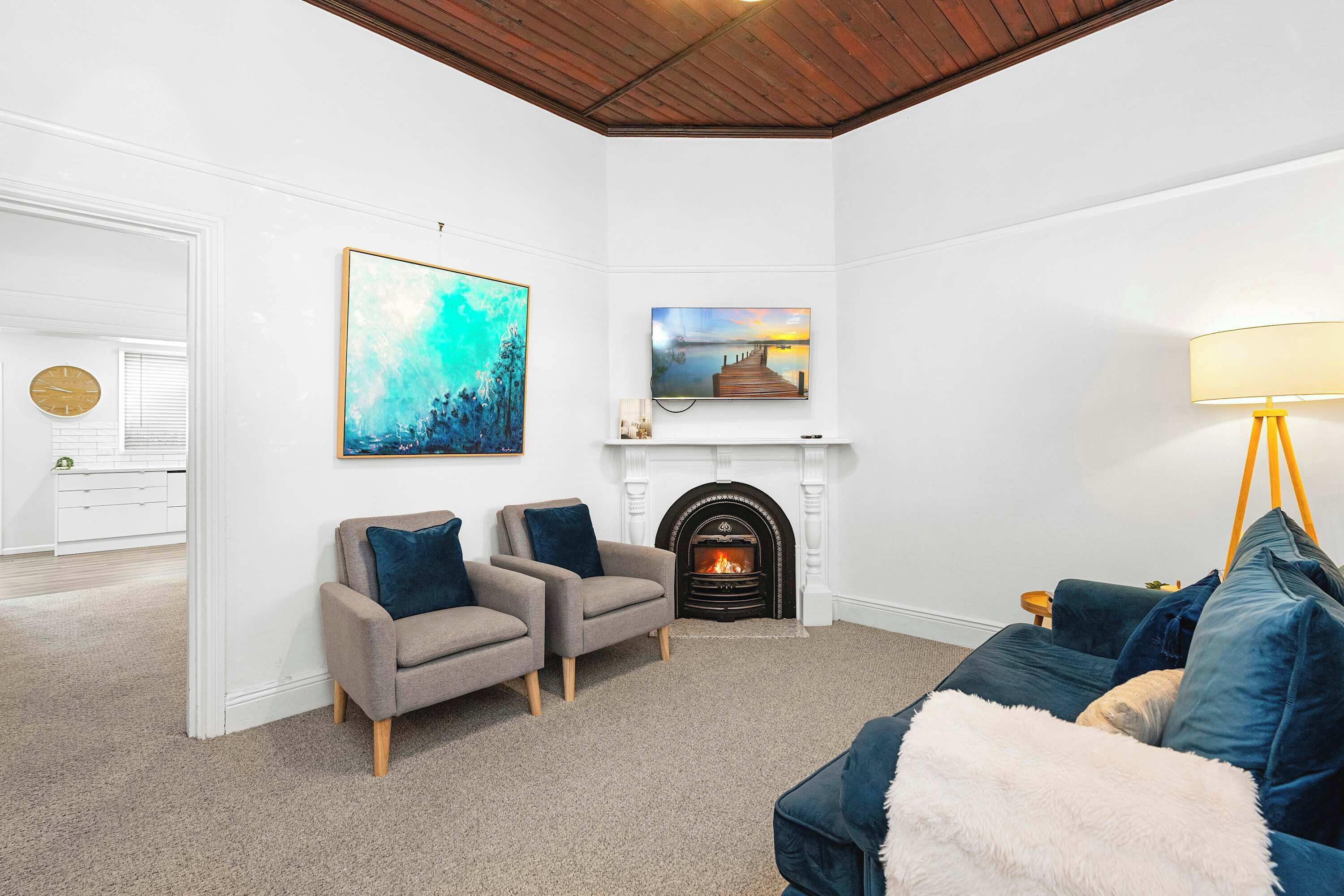 A living room with a fireplace, two armchairs, a sofa, and artwork on the walls.