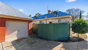 Ein Wohnhaus mit Garage, einem eingezäunten Garten und einem Baum.